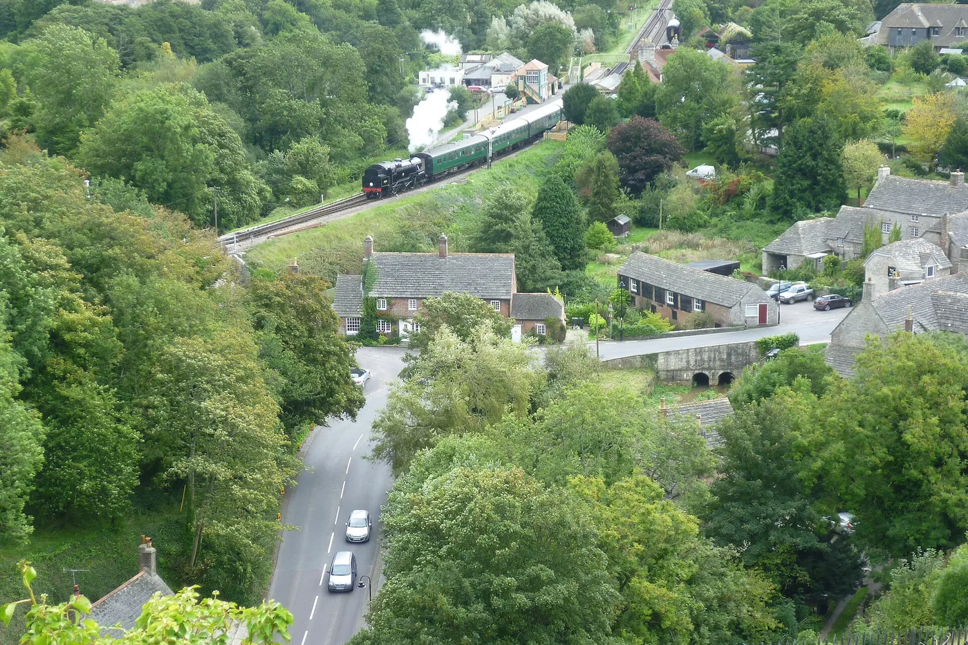 A Swanage Railway steam train leaving Corfe Castle station, seen from the castle above the village