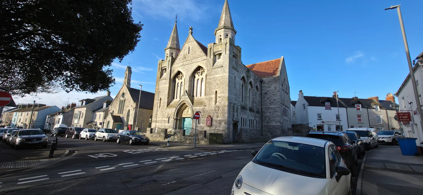 Easton Methodist Church seen from the street, its twin stone spires and red tiled roofs above the shops and houses of Easton Square