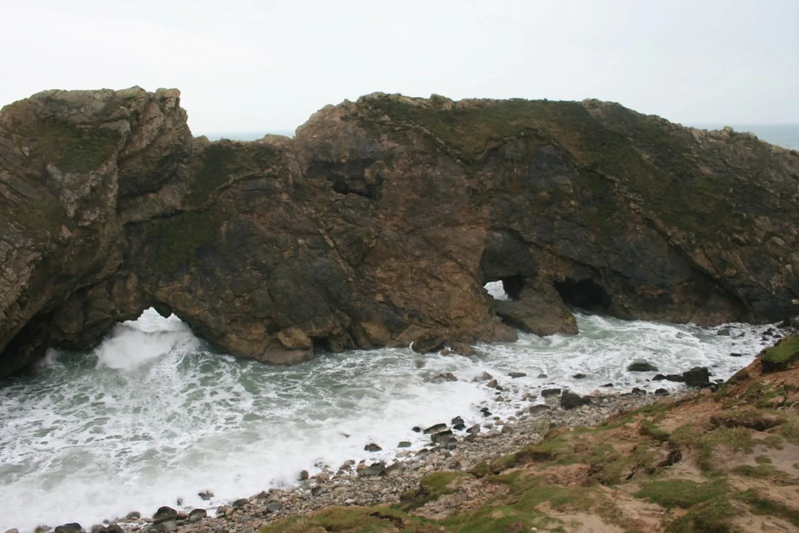 Stair Hole at Lulworth, a small rocky inlet where waves break through an arch in a wall of dark folded rock