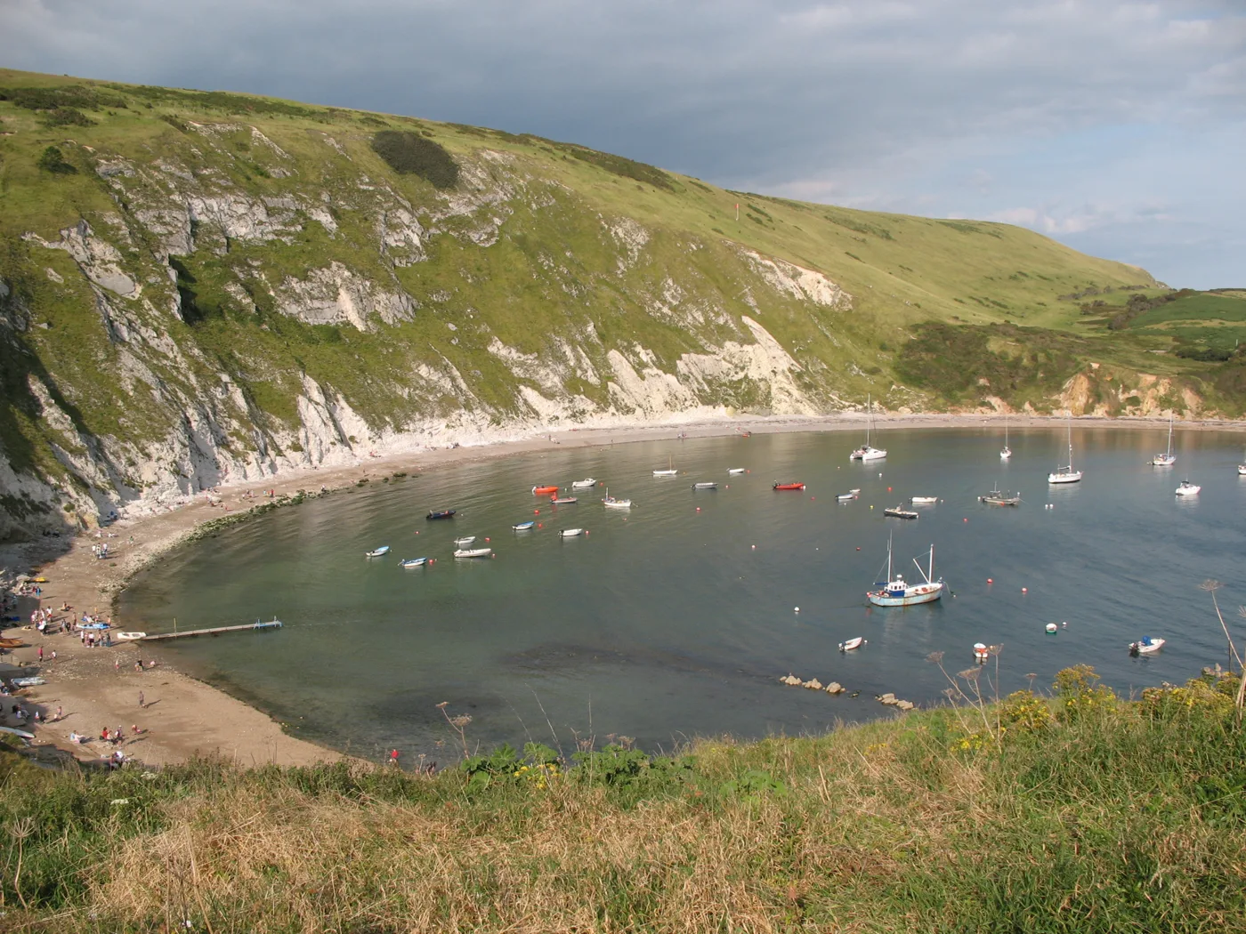 Lulworth Cove from the hillside above, with boats moored in the bay