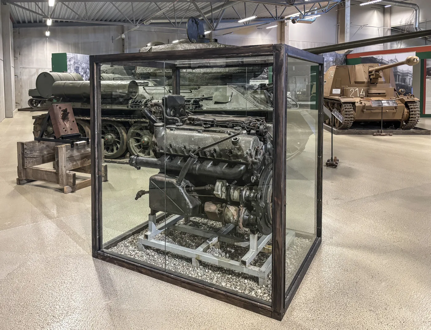 A large King Tiger engine in a glass display case at Arsenalen, with other tanks behind it