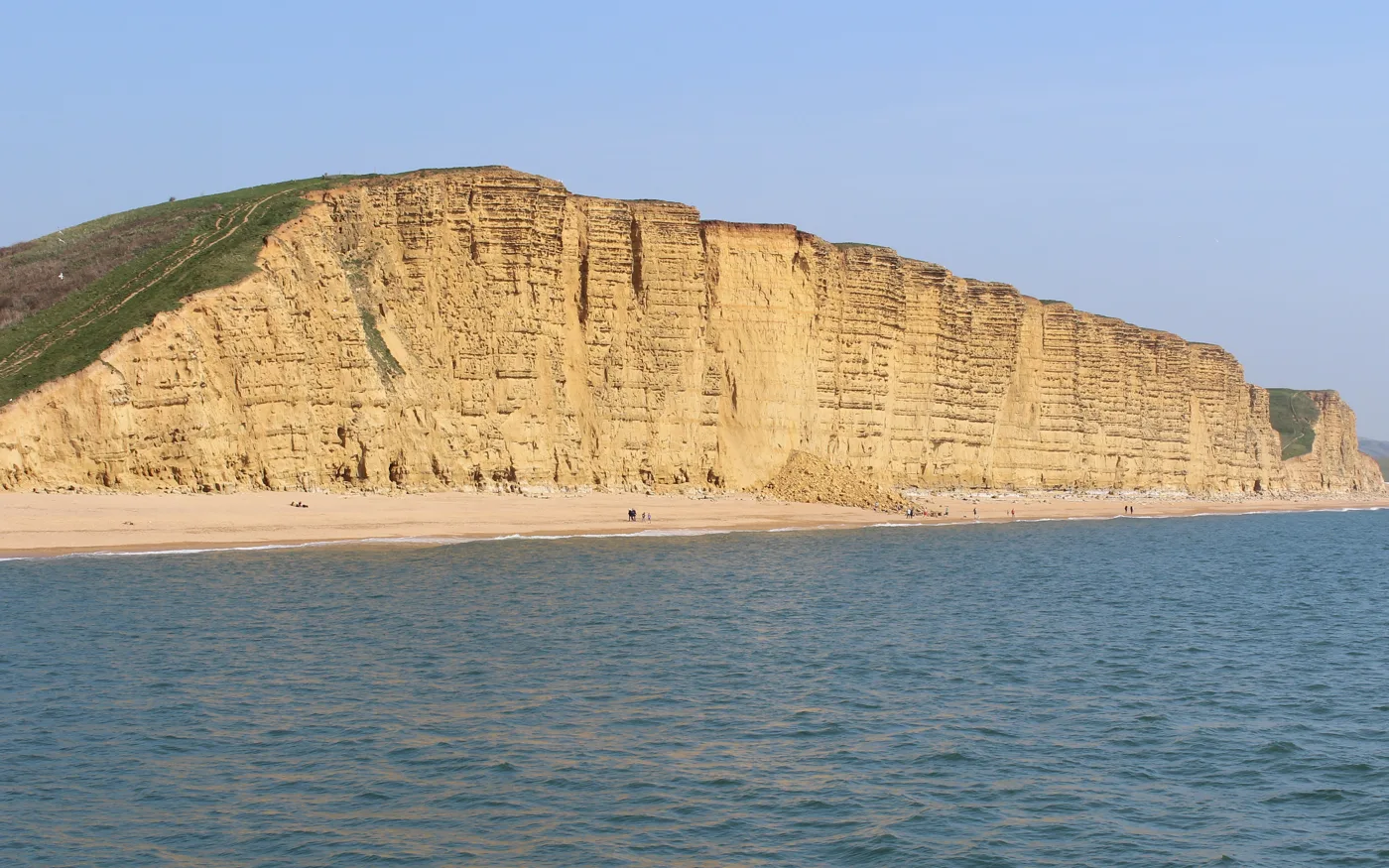 East Cliff at West Bay seen across the water, with a heap of fallen rock at the foot of the cliff